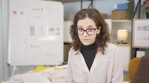 Woman With Glasses Speaking to Camera at Desk