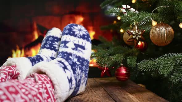 Legs in Christmas Red Pants and Homemade Warm Socks with Reindeer on the Background of Christmas
