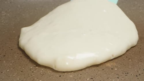 I turn the pancake over in a frying pan with a silicone spatula. extreme close-up. Slow motion