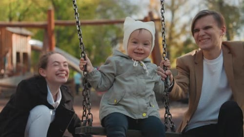 Happy Family with Baby on Swing in Park