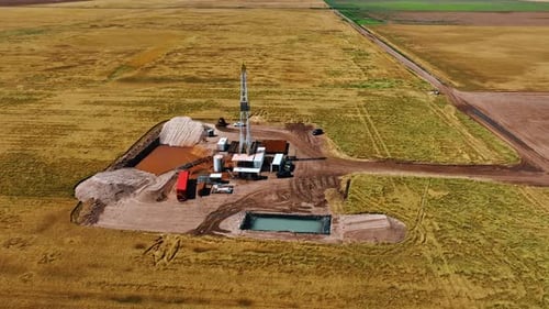 Flight around the small site for natural resources drilling in the vast field.