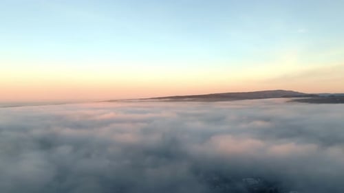 Mesmerizing aerial journey as clouds glow in golden sunrise, leading toward majestic mountain