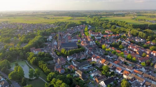 Drone view of a picturesque European town with a towering church, red-roofed houses, winding