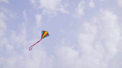 A Multicolored Kite Flying High in the Sky Under the Gusts of Wind