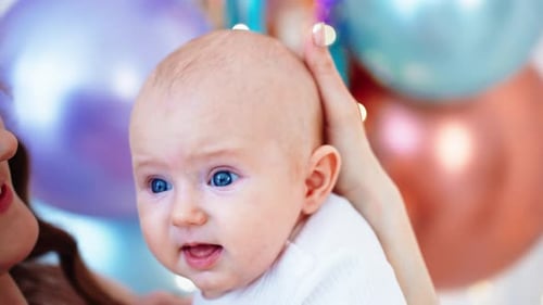 Smiling Woman Holds Baby Close at Celebration