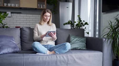 Woman Using Tablet at Home on Couch