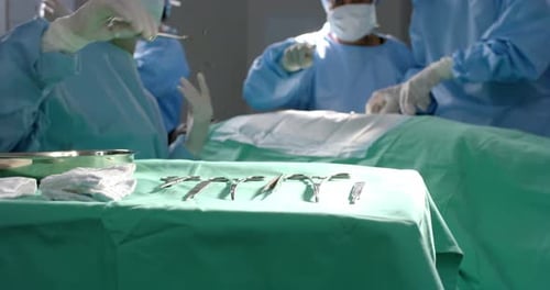 Diverse surgeons operating on patient using surgical instruments in operating theatre, slow motion