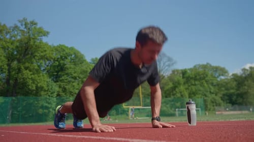Man Doing Pushups on Stadium Track During Training Session