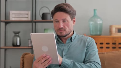 Man Uses Tablet Device Indoors At Home