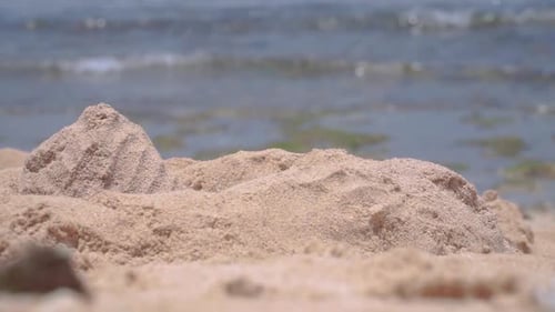 Close up focused sandy beach blurred sea waves. Beach sand in sunny summer exotic shore. Close up sh
