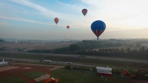 Aerial view with drone approaching hot air balloons and white castellated highway in the background,