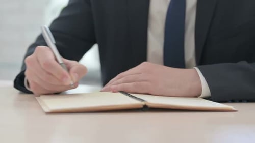 Nahaufnahme eines Geschäftsmannes, der auf ein Notizbuch schreibt