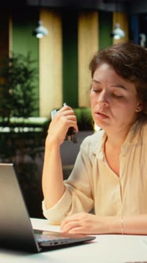 Woman cooling herself with stapler at her desk
