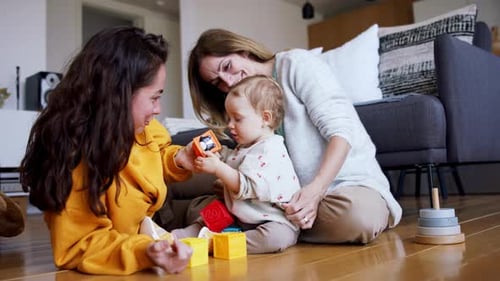 Two women and baby play together indoors