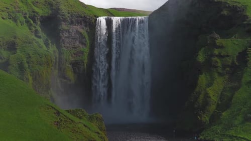 Aerial View of Skogafoss Waterfall Cascading Over Green Hills in Iceland