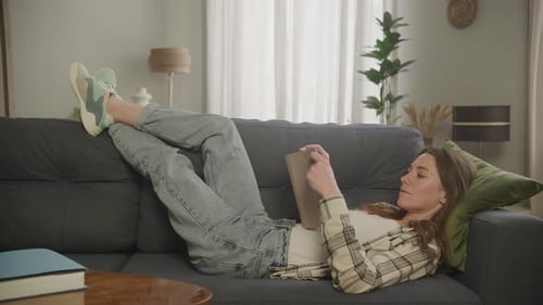 Woman Relaxes Reading Book on Sofa