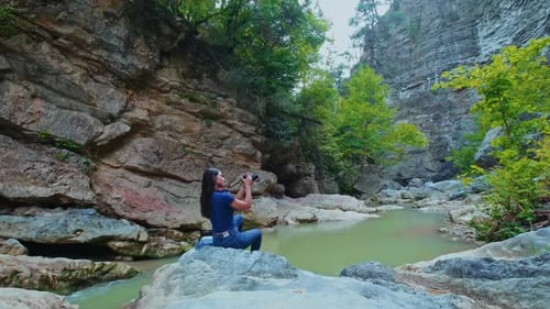 Weibliche Reisende fotografiert auf Felsen in der Nähe von Forest Creek in friedlicher Natur