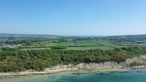 Aerial landscape, showing the shoreline and blue sea on the Isle of Wight on a bright blue sky day.