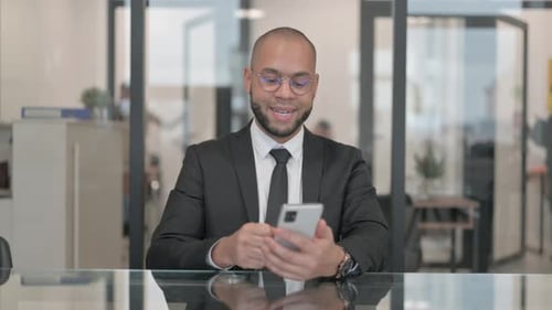 Man Celebrates Good News on Smartphone in Office