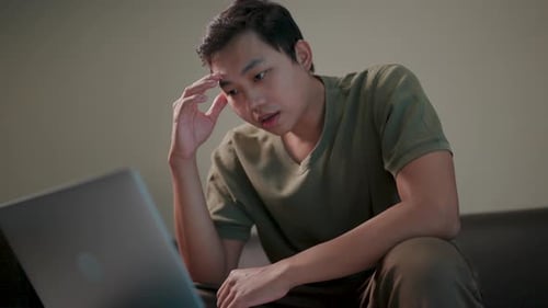 Man Working on Laptop with Thoughtful Expression