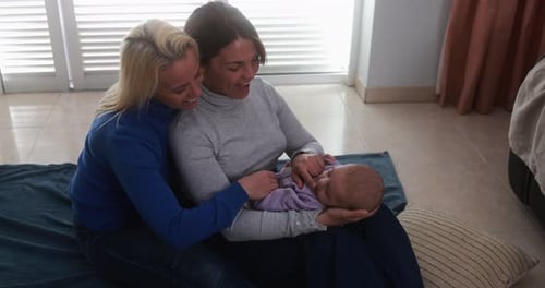 Happy female gay couple having tender moment with their baby son at home - Family, lgbt and love