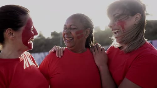 Senior multiracial red football sport fans celebrating while watching soccer match game at stadium