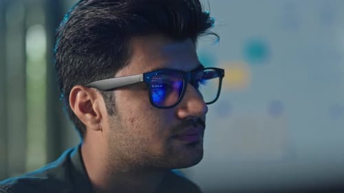 Profil eines jungen männlichen Entwicklers mit Brille im Büro
