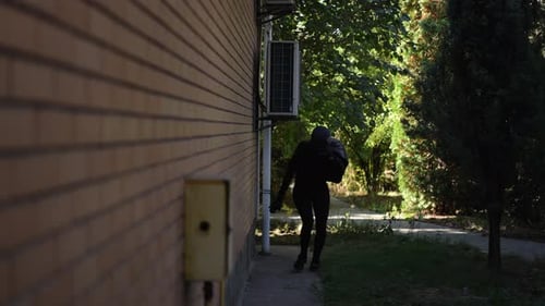 Slow Motion Masked Girl Burglar Running with Stolen Bag Along House Wall