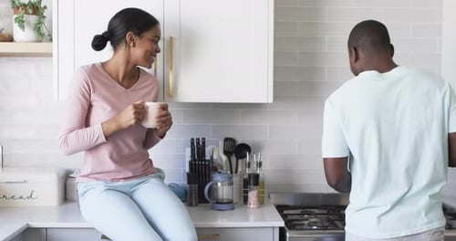 Woman Talking To Man Cooking in Kitchen