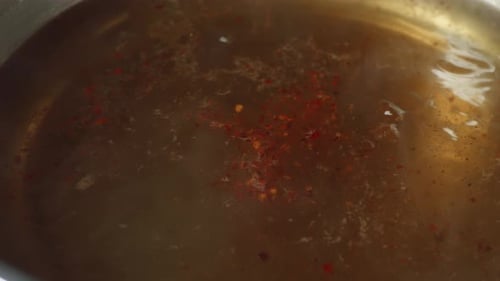 Close Up Of Chili Being Sprinkled Into The Boiling Soup Pot. Sukiyaki Or Shabu