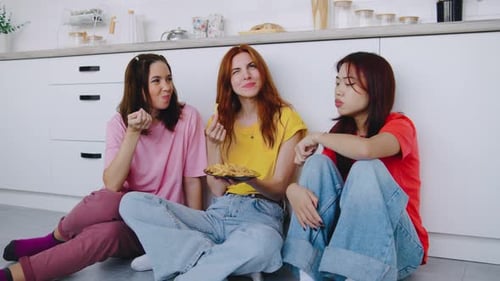 Three Friends Enjoying Fries Together in Kitchen