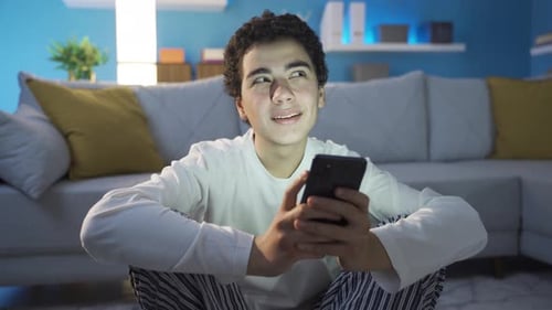 Teenage Boy Using Smartphone in Living Room