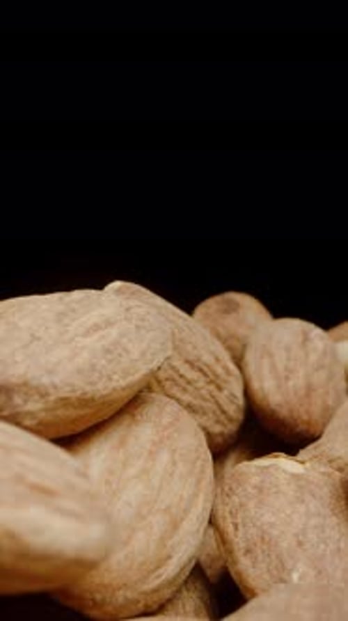 Vertical video. I Pour a Handful of Almonds from the Hand while the Camera Moves Forward.