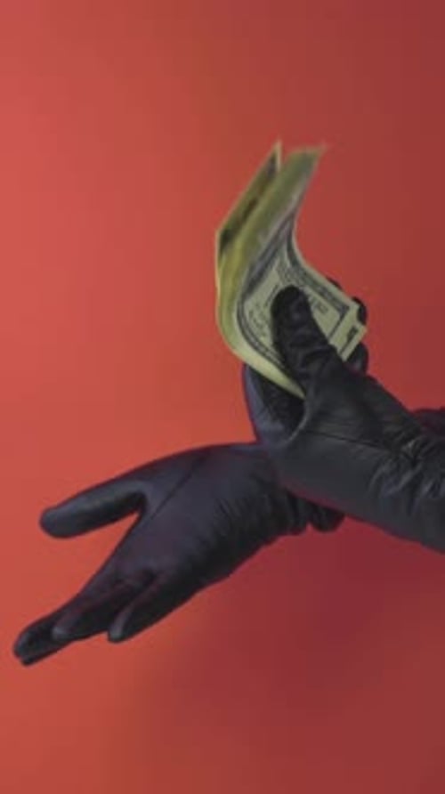 Money Stack Applause mit schwarzen Lederhandschuhen auf rotem Hintergrund