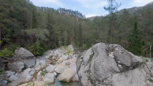 Blick aus der Vogelperspektive auf den Wald, massive Felsbrocken und einen Bach im Canyon