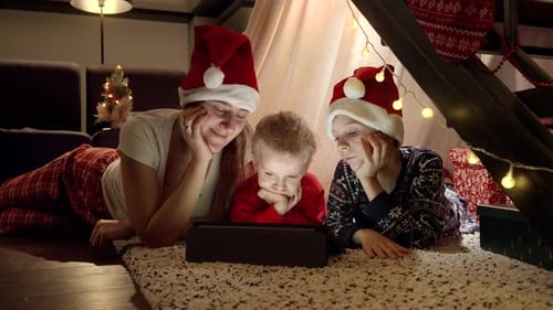 Family in Santa Hats Watch Tablet at Christmas