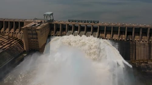 High angle drone view of dam wall with sluice gates releasing water.