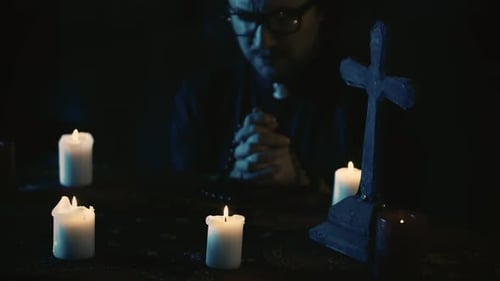 Man Praying by Candlelight with Cross and Rosary