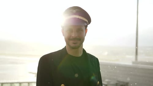 Young Adult Pilot Wearing Hat and Coat at Airport