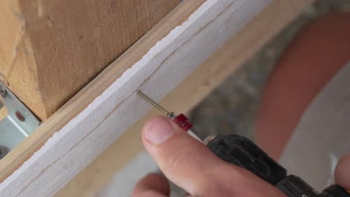 A Man Hands Using a Power Tool Fastens a Board with a Screw Slow Motion