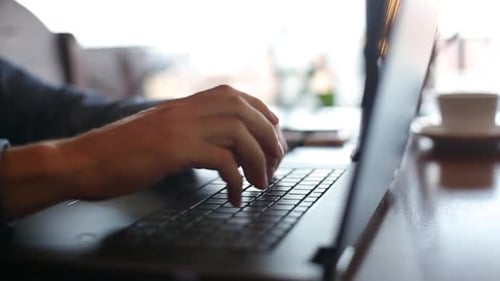 Câmera desliza pelas mãos de um freelancer digitando no teclado do laptop em câmera lenta Empresário trabalhando