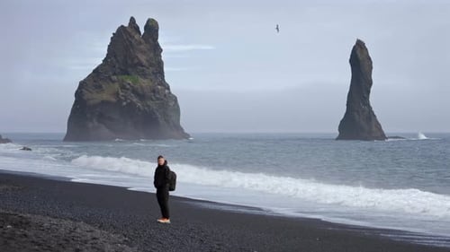 Man Standing By Ocean on Reynisfjara Beach Iceland