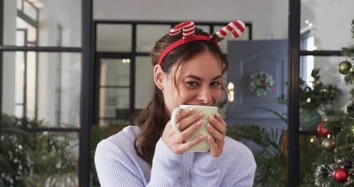 Smiling Woman with Festive Mug by Christmas Tree