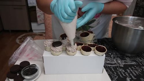 Eine Frau füllt Waffeltüten mit Zephyr. Es schmückt mit Keksen. Nahaufnahme
