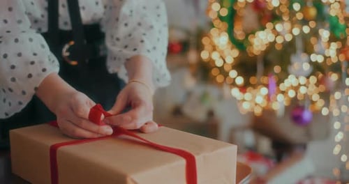 Wrapping a Christmas Present with Red Ribbon