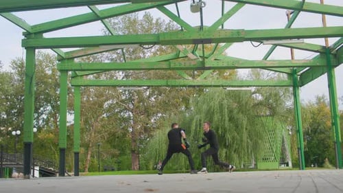 Two young men sparring outdoors in urban park