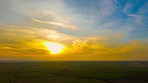 Golden Sunset Timelapse Over Rural Countryside Landscape with Glowing Sun and Dramatic Sky Colors