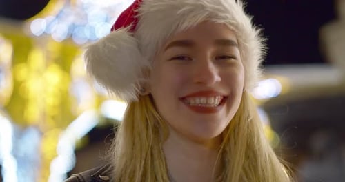 Smiling Young Woman Wearing a Santa Hat at Night