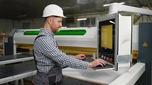 Factory Worker Operating CNC Cutting Machine