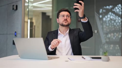 Man Working at Desk Using Phone in Office